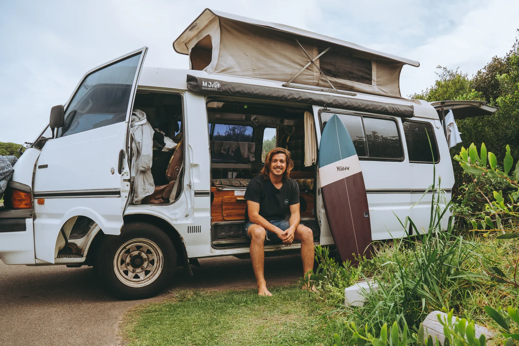 Custom Yugen board beside a campervan